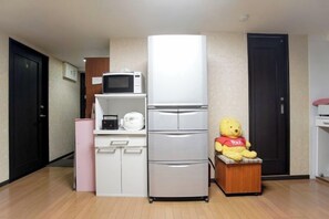 A compact kitchen with a microwave, refrigerator, and a teddy bear on a small table. - Tokyo Wenjuan's Guesthouse (Tokyo)