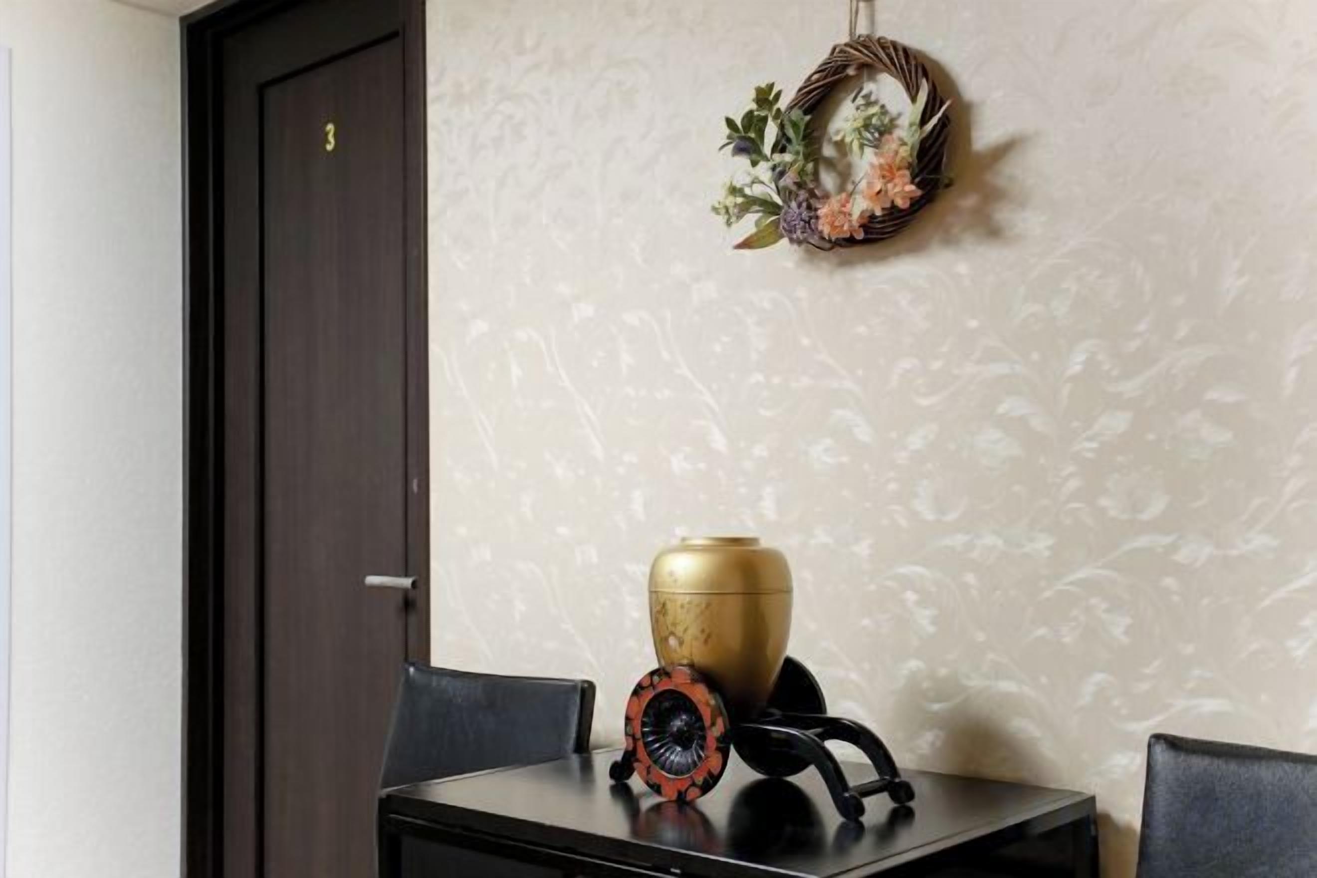 A dining area with a table, chairs, a decorative vase, and a wall-mounted ornament.