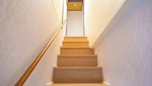 Una escalera de madera con barandilla que lleva a una plataforma con una lámpara.