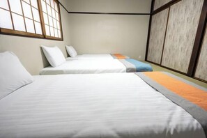A hotel room with two beds, a large window, and a sliding door.
