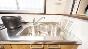 Una cocina con un lavamanos de acero inoxidable, un electrodoméstico negro sobre la encimera y armarios de madera con cajones.