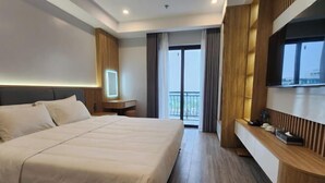 Une chambre d’hôtel moderne avec un grand lit, une table de chevet, une télévision et un balcon avec des rideaux.