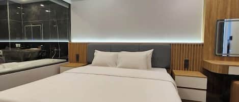 A modern hotel room with a large bed, a built-in bathtub, and a wooden panel wall.