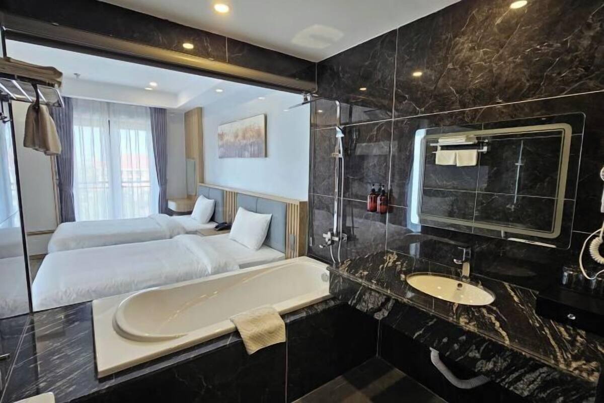Een moderne hotelbadkamer met een groot bad, een aparte douche en een wastafel met spiegel.