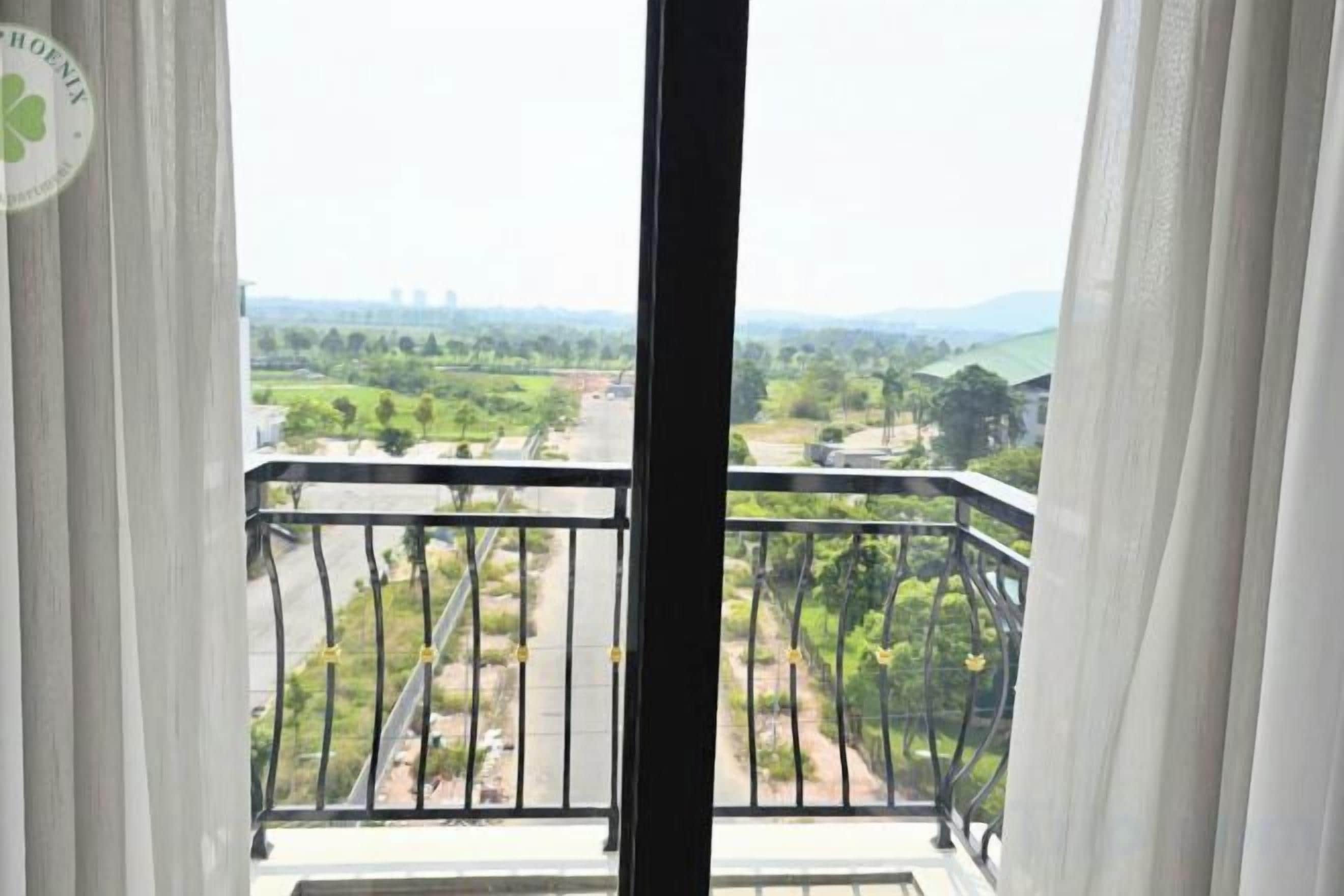A balcony with a view of a green landscape and distant buildings.