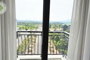 Un balcón con vistas a un paisaje verde y edificios al fondo.