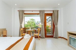 A hotel room with a bed, a desk, a chair, a TV, and a balcony with curtains.