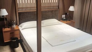 A hotel room with a bed, two bedside tables, a nightstand, a lamp, and a trash bin. - Good Luck Hostel (Phnom Penh)