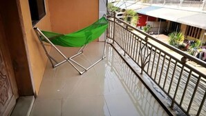 A balcony with a green hammock, metal railing, and a tiled floor. - Good Luck Hostel (Phnom Penh)