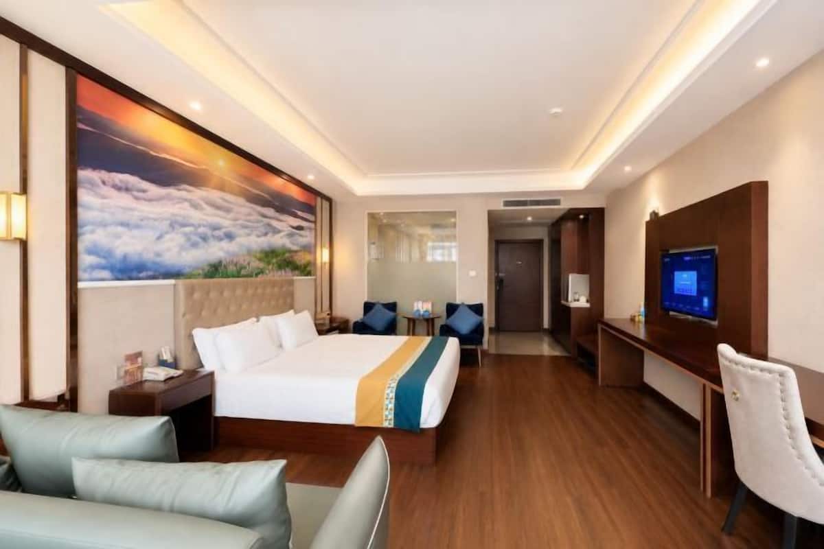 A hotel room with a bed, a TV, a desk, and a chair.