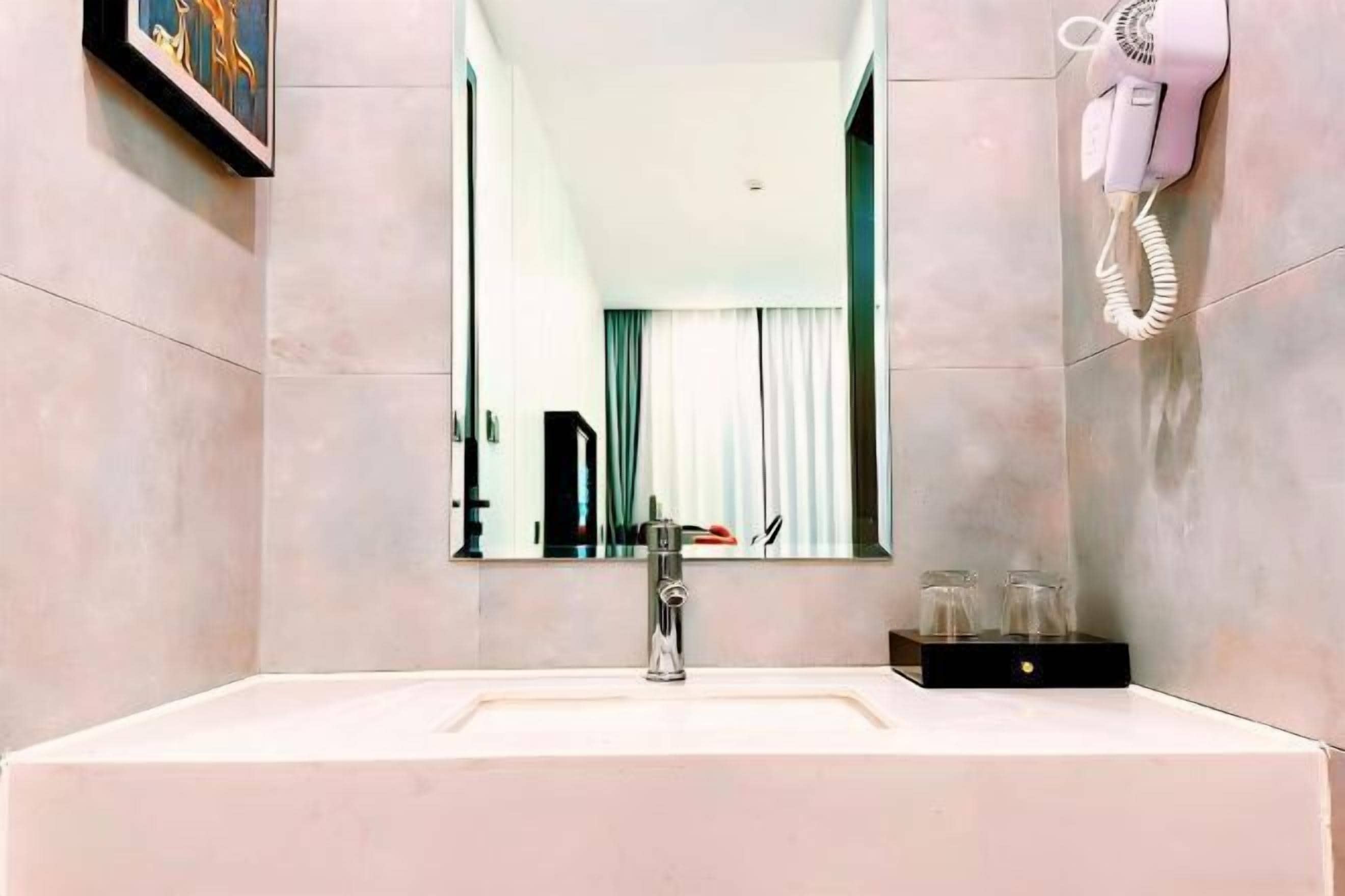 A bathroom with a sink, mirror, and hairdryer mounted on the wall.