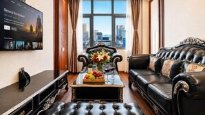 Ein modernes Wohnzimmer mit Stadtblick, einem Flachbildfernseher, einem Ledersofa und einem Couchtisch mit Blumenarrangement.