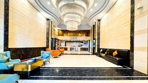 Eine großzügige Lobby mit einer zentralen Rezeption, modernen Sitzgelegenheiten und einer großen Chandelier.