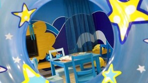 A child's playroom with a blue and yellow color scheme, featuring a bed, a table with books, and a chair. - Club Med Cherating Beach (Balok)