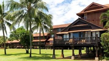 A hotel with multiple buildings, palm trees, and a well-maintained lawn.