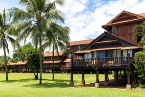 Un hotel con varias edificaciones, palmeras y un césped bien cuidado.