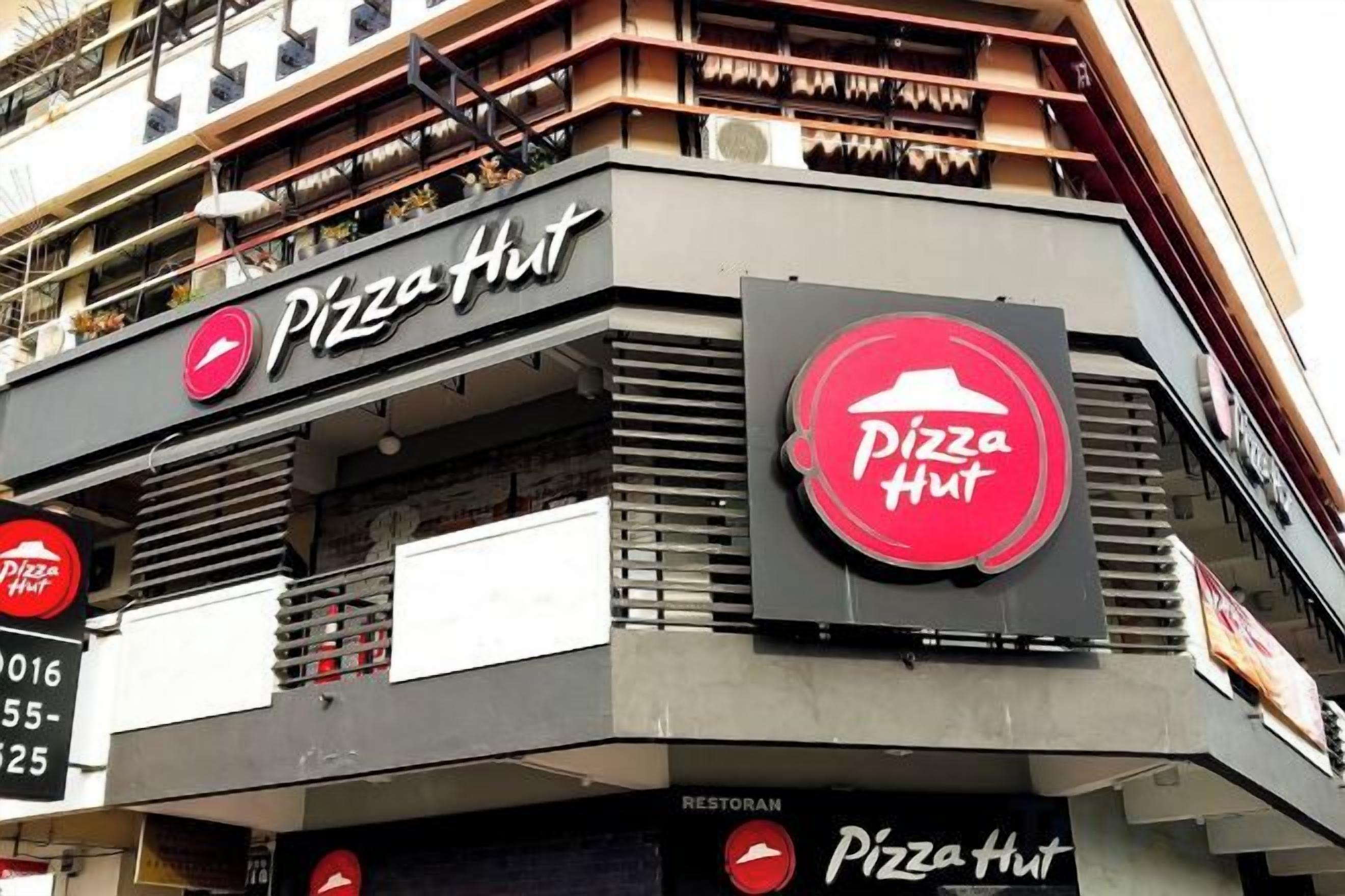 Un restaurante Pizza Hut con un letrero llamativo, un balcón y un escaparate.
