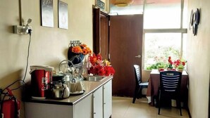 Cucina con macchina da caffè, bollitore e lavandino. Angolo ristoro con tavolo e sedie.