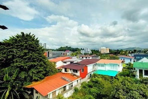 A residential area with houses, some with red roofs, and a few with green roofs. There are trees and a hill in the background. - MB Hotel (Kota Kinabalu)
