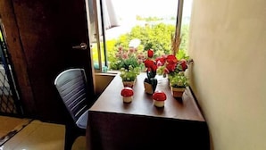 Una stanza con un tavolo vicino a una finestra, una sedia e diverse piante in vaso.