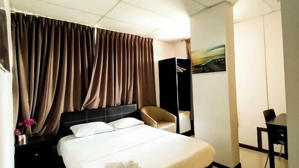 Una camera d'albergo con un letto, una sedia, una scrivania e un armadio.