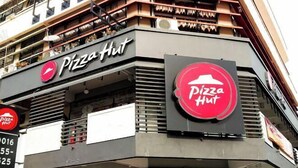 Un ristorante Pizza Hut con una facciata moderna, diversi loghi Pizza Hut e un numero di telefono ben visibile.
