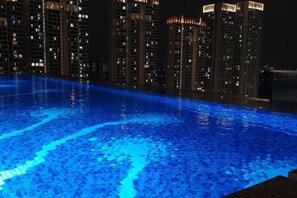 A swimming pool with a blue tint, surrounded by high-rise buildings at night. - Pavillion Bukit Jalil 【Walk 2 mins】Stylish Lily Studio 2-4 Pax (Kuala Lumpur)