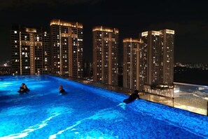 A nighttime swimming pool with illuminated buildings in the background. - Pavillion Bukit Jalil 【Walk 2 mins】Stylish Lily Studio 2-4 Pax (Kuala Lumpur)