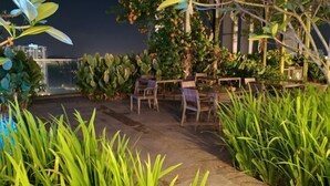 A rooftop garden with a seating area, lush greenery, and a view of the cityscape. - Pavillion Bukit Jalil 【Walk 2 mins】Stylish Lily Studio 2-4 Pax (Kuala Lumpur)