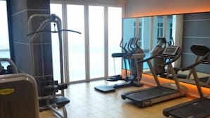 Une salle de sport équipée de tapis de course, de vélos elliptiques et de matériel de musculation.