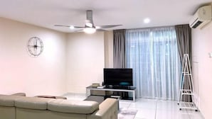 Un salon moderne comprenant un canapé, un téléviseur, un ventilateur de plafond et un appareil de climatisation.