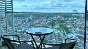 Un balcon avec une table et des chaises, donnant sur un paysage urbain avec des immeubles et une enseigne.