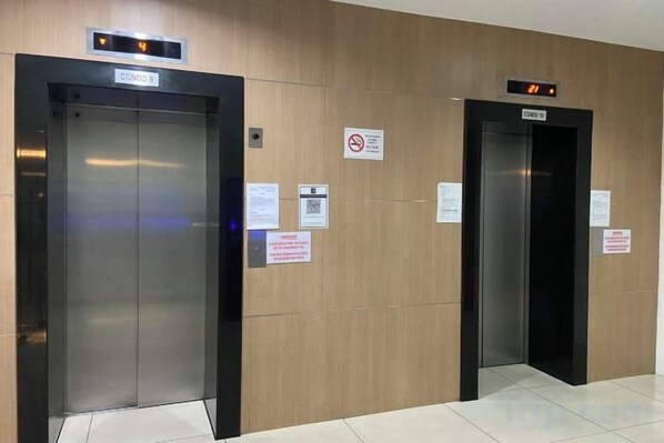 Two elevators with digital displays, wooden paneling, and informational signs. - KSL D’Esplanade Apartment by SC Homestay (Johor Bahru)