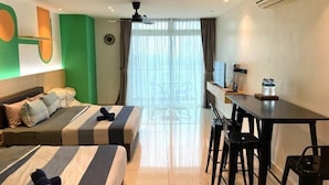 Une chambre d’hôtel avec deux lits, un bureau, des chaises, un climatiseur et une grande fenêtre avec des rideaux.