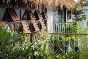 A thatched-roof structure with wooden slats, surrounded by lush greenery and a metal fence. - Private Nongnia Beach Villas (Hoi An)