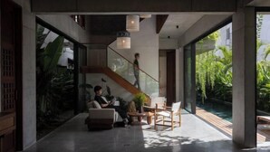 Um interior moderno com escada, área de estar e vista para uma piscina.