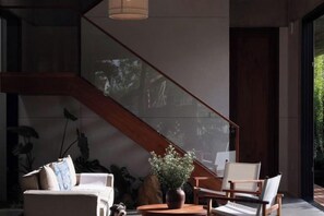 A modern interior with a staircase, seating area, and a potted plant. - Private Nongnia Beach Villas (Hoi An)