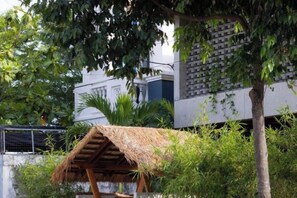 A thatched-roof structure, a tree, and a building with a brick wall. - Private Nongnia Beach Villas (Hoi An)