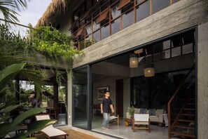 A modern building with a glass facade, wooden deck, and indoor seating area. - Private Nongnia Beach Villas (Hoi An)