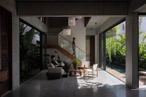 A modern interior with a staircase, seating area, and large windows. - Private Nongnia Beach Villas (Hoi An)