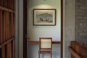 A framed picture of a beach scene on a wall, a wooden chair, and a door with a wooden frame.