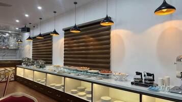 A buffet setup with multiple serving stations, overhead lighting, and a marble countertop.