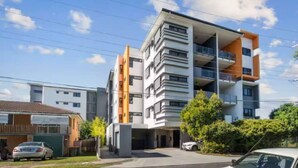 A multi-story residential building with balconies, a garage, and a parking area. - 2-Bedroom Apartment Balcony Close to All Hotspots (MacGregor)