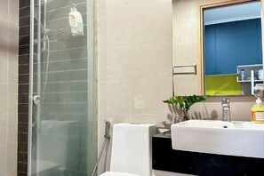 Une salle de bain avec une douche à parois de verre, un lavabo blanc et un miroir au-dessus.