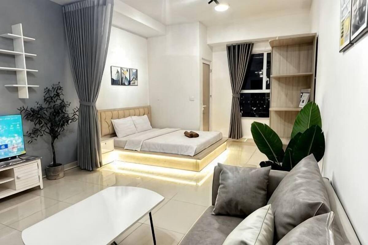 Un salon moderne avec un canapé, un lit, une télévision et une plante.