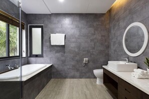 Ein modernes Badezimmer mit Badewanne, Waschbecken, Toilette und einem großen Spiegel.