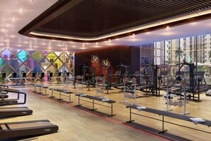 Ein modernes Fitnessstudio mit unterschiedlichen Trainingsgeräten, Holzboden und großen Fenstern.