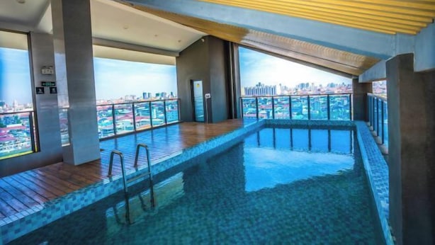 A modern indoor swimming pool with a view of a cityscape. - Ark House (Phnom Penh)