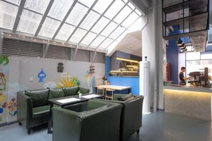 Un interior moderno con techo alto, una zona de bar y diferentes disposiciones de asientos.