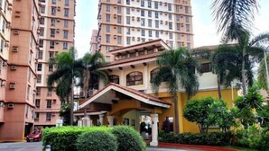 Un edificio residencial de varios pisos con un patio central, rodeado de abundante vegetación y palmeras.
